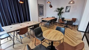 Una sala de reuniones moderna con una mesa de madera, sillas negras y marrones, e iluminación colgante.