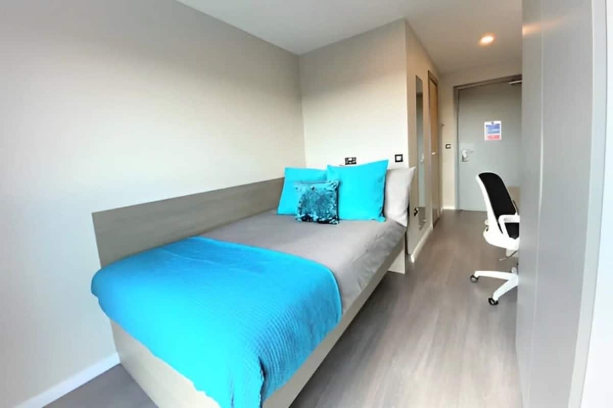 A modern bedroom with a bed, a desk, and a chair.