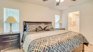 A bedroom with a bed, nightstands, a ceiling fan, and a bathroom visible through an open door. - Near State Parks! Crystal River Home w/ Hot Tub (Crystal River)