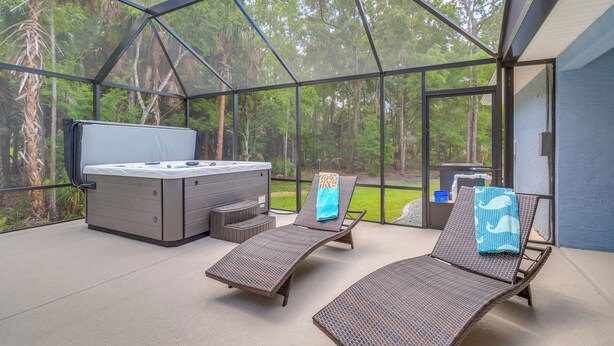 A glass-enclosed outdoor area with a hot tub, lounge chairs, and a small table. - Near State Parks! Crystal River Home w/ Hot Tub (Crystal River)