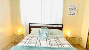 A neatly made bed with a blue blanket, two bedside lamps, and a wall quote. - Sea-la-Vie Retreat: Parking Included & Fire Pit (San Diego)