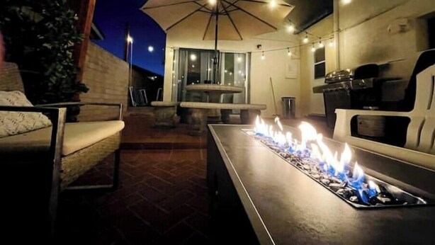 An outdoor patio area with a fire feature, seating, and an umbrella providing shade. - Sea-la-Vie Retreat: Parking Included & Fire Pit (San Diego)