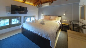 A bedroom with a large bed, a desk, and a TV mounted on the wall. - Villa Ambrosia, Beach house, Pelion II (Platanidia)