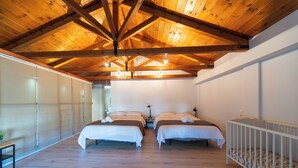A bedroom with two beds, wooden ceiling beams, and a crib. - Villa Ambrosia, Beach house, Pelion II (Platanidia)