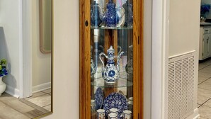 A wooden display cabinet with glass doors containing various ceramic items.