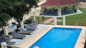 A rectangular swimming pool with lounge chairs and a covered seating area. - MG INN & SUITES (Zapata)