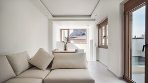 Ein modernes Wohnzimmer mit einem beigefarbenen Sofa, einem Holztisch und Blick auf ein traditionelles Gebäude durch große Fenster.