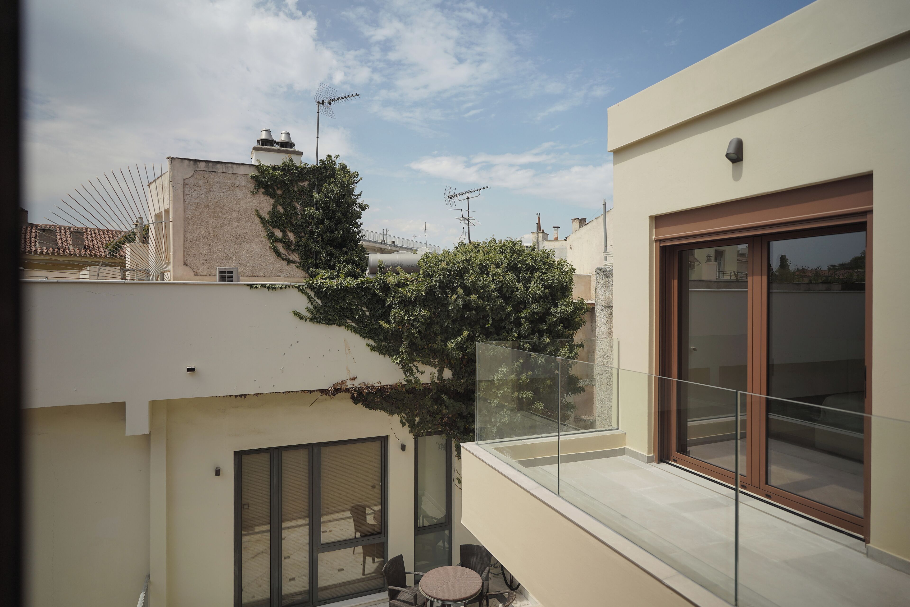 A modern apartment with a balcony, large windows, and a view of neighboring buildings.