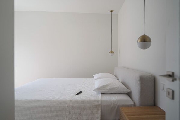 A minimalist bedroom with a single bed, a bedside table, and two pendant lights. - Plaka House - Apartments (Athens)