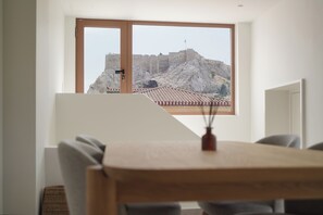 Una habitación con un amplio ventanal que da a una pared de piedra histórica y un tejado de tejas.