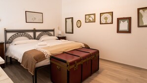 A neatly made bed with a brown blanket, a wooden nightstand with a lamp, and a vintage suitcase on the floor. - Casa Mameli by Wonderful Italy (Conversano)
