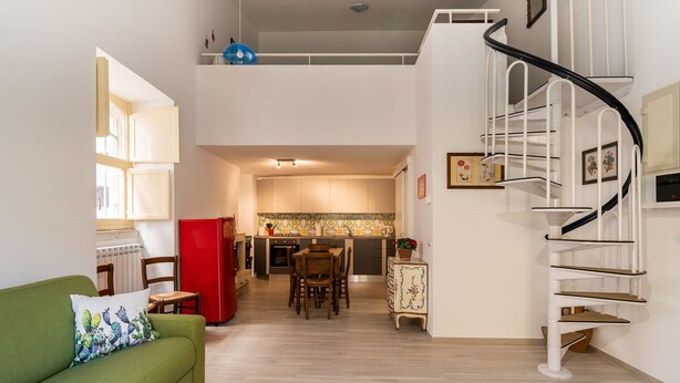 A modern apartment with a green sofa, a dining area, a kitchen, and a spiral staircase. - Casa Mameli by Wonderful Italy (Conversano)