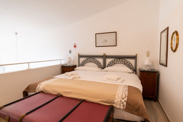 A neatly made bed with a headboard, a bedside table with a lamp, and a small decorative item on the wall.