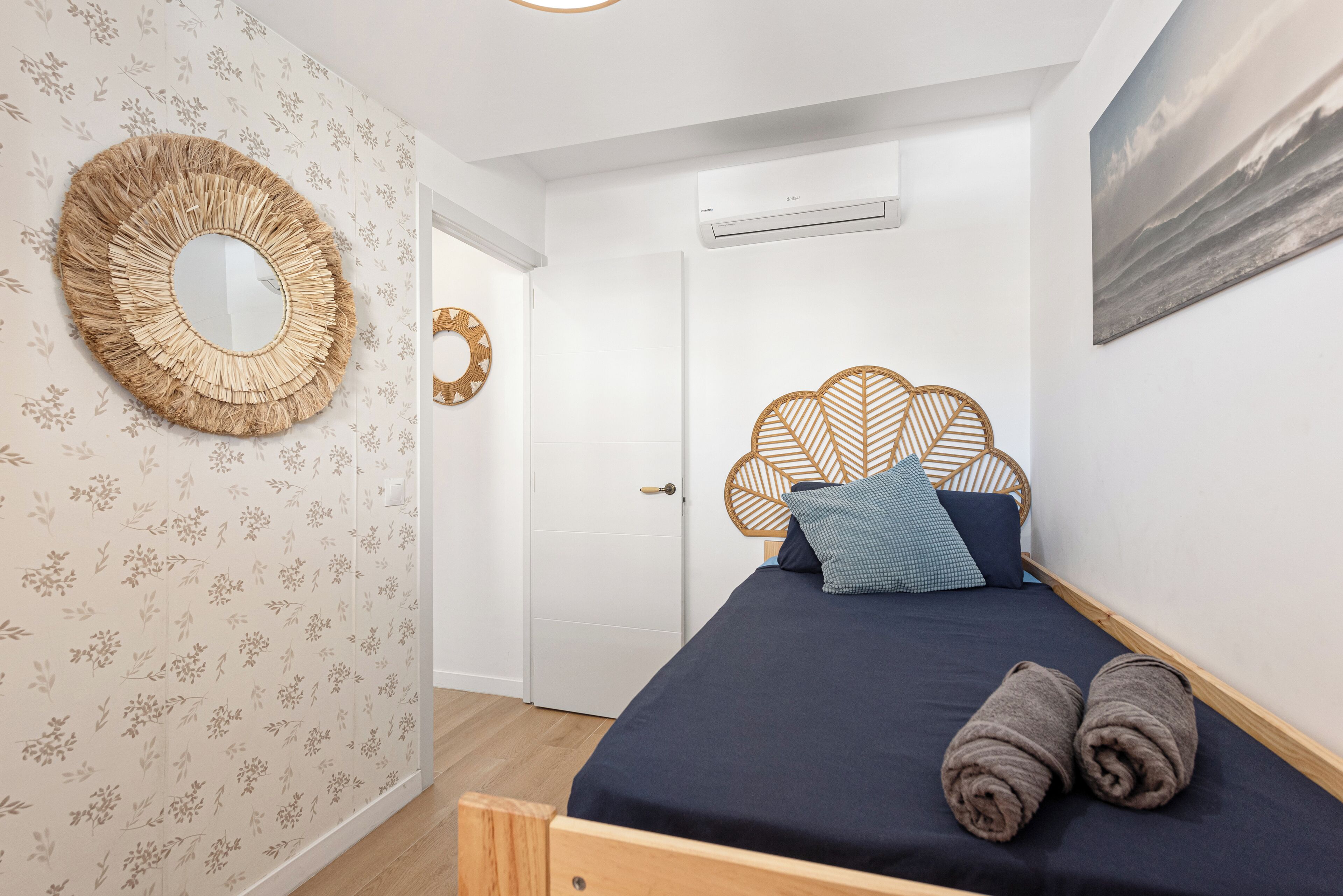 Une chambre à coucher avec un lit, un miroir rond et un climatiseur fixé au mur.
