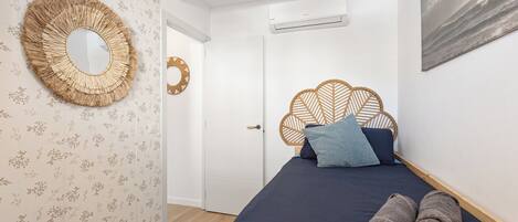 Une chambre à coucher avec un lit, un miroir rond et un climatiseur fixé au mur.