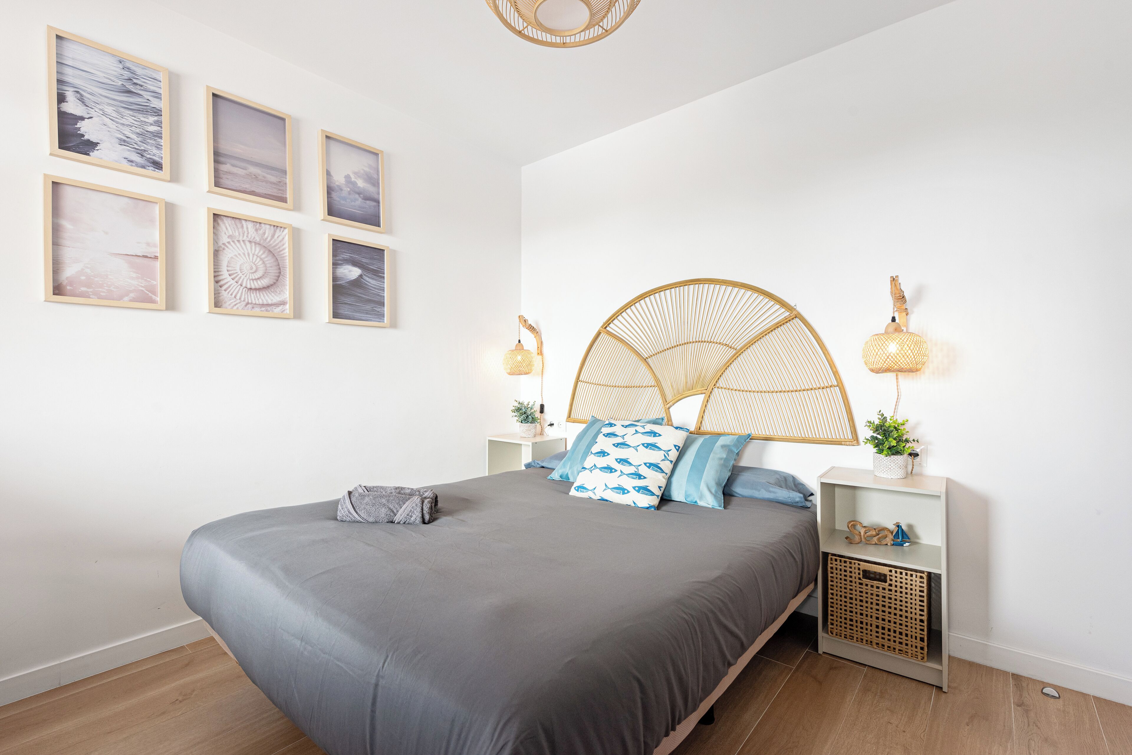 Un dormitorio moderno con una cama grande, dos mesitas de noche con lámparas y seis cuadros enmarcados en la pared.