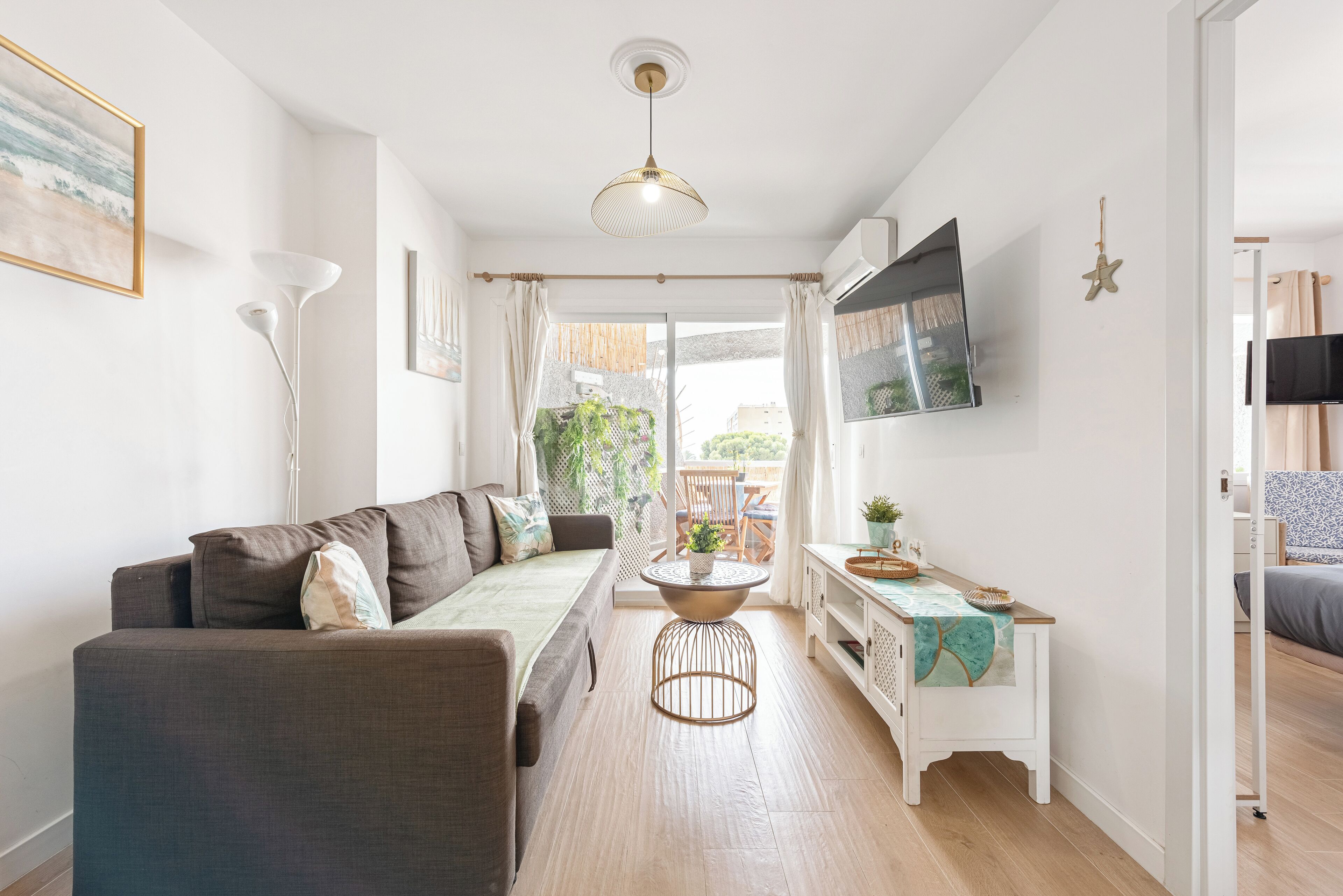 A modern living room with a sofa, a coffee table, and a TV mounted on the wall.