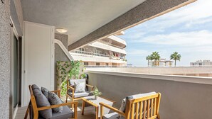 Un balcón con mobiliario de madera, vista a un crucero y palmeras.
