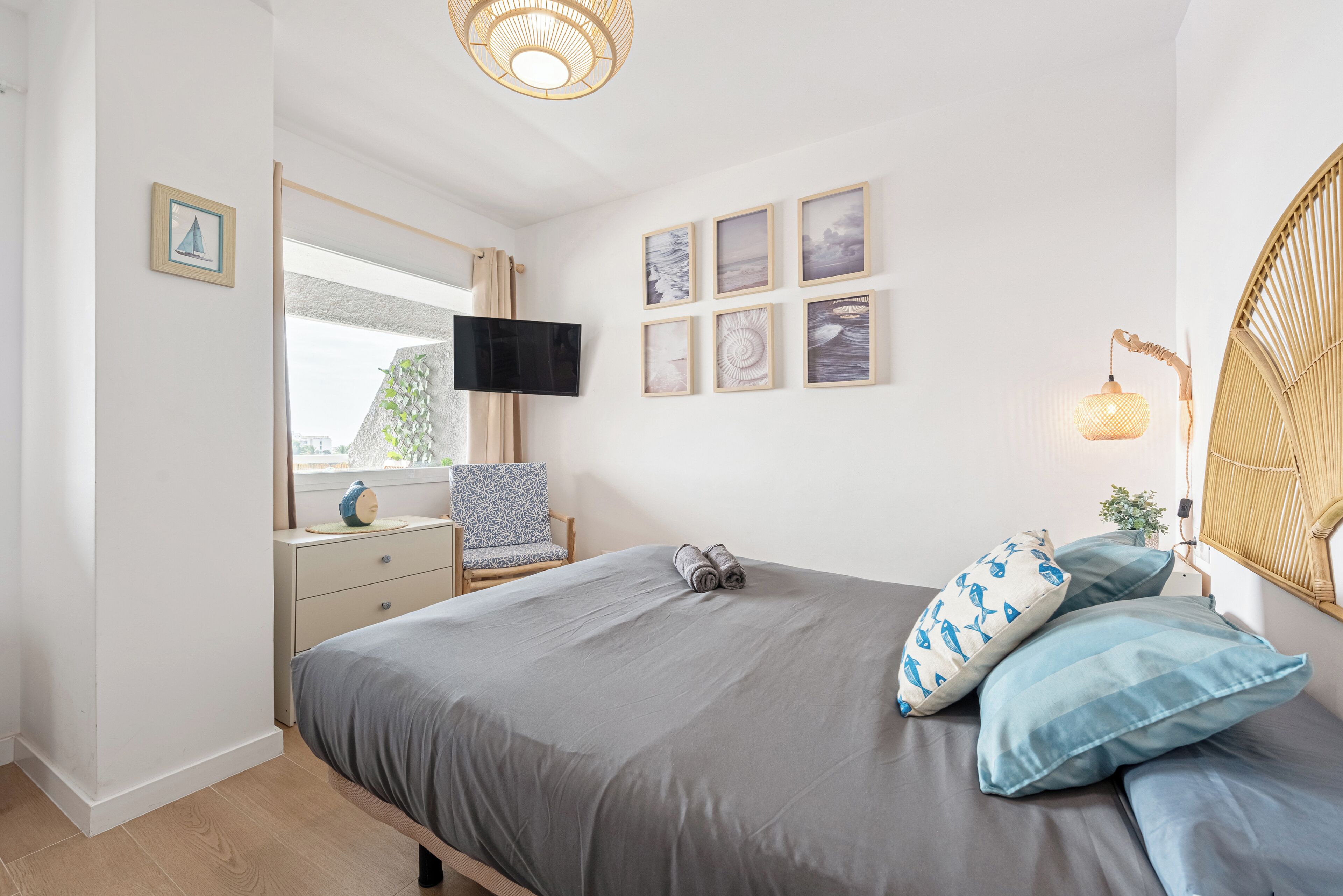 Un dormitorio con cama, televisión, ventana y decoración en la pared.