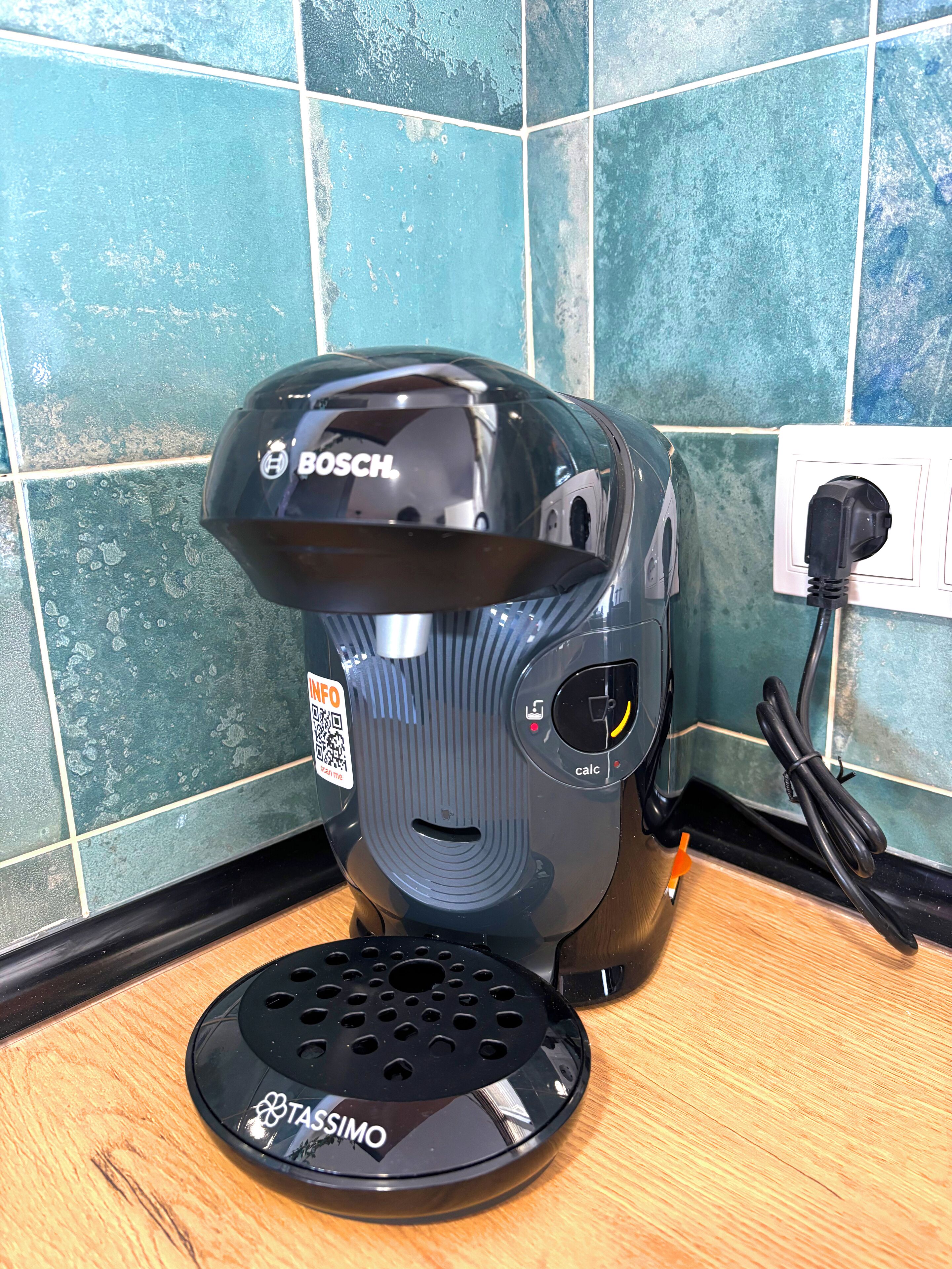 A Bosch coffee maker with a Tassimo pod holder on a wooden countertop.