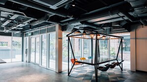 Un interior espacioso con ventanas amplias, suelo de patrón geométrico y estructura de silla colgante.