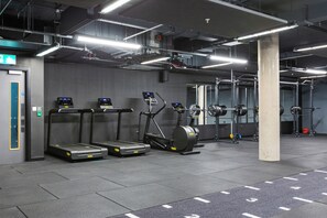 Une salle de sport équipée de tapis de course, d’un appareil elliptique et de machines de musculation.