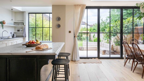Eine moderne Küche mit einer großen Kochinsel, Barhocker und einem Essbereich mit Holzkästen.