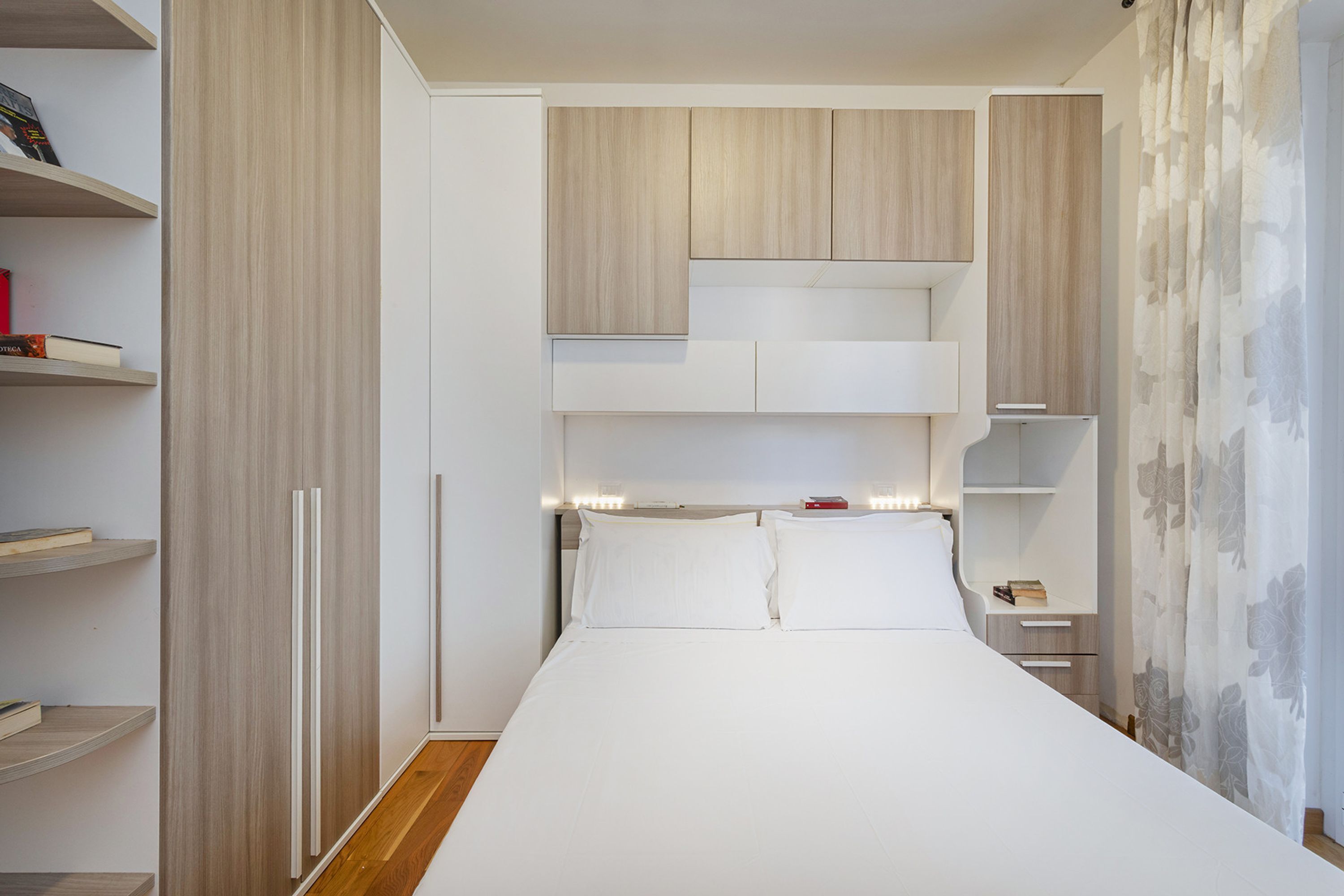 Une chambre à coucher avec un lit, des étagères intégrées et une table de chevet.