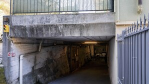 En smal, svagt upplyst underjordisk gång med betongväggar, en metallgrind och en cykel som står parkerad inuti.