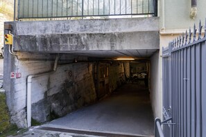 Kapea, hämärästi valaistu maanalainen käytävä, jonka seinät ovat betonia, ja jossa on metallinen portti sekä sisällä pyörä.