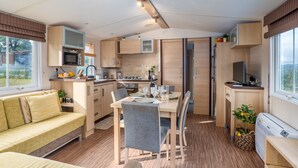 A compact kitchen with a dining area, built-in appliances, and a sofa.