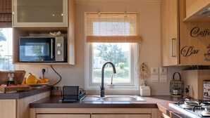 A modern kitchen with a built-in microwave, a sink with a faucet, wooden cabinets, and a window with blinds.