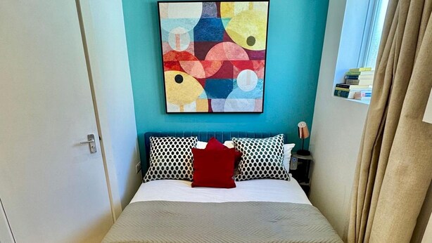 Una habitación de hotel con una cama, almohadas, una manta y dos toallas enrolladas.