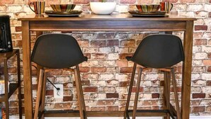 Una mesa de comedor con dos sillas negras, una planta en maceta y una cafetera.
