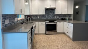Una cocina moderna con armarios blancos, estufa de acero inoxidable y salpicadero de azulejos.