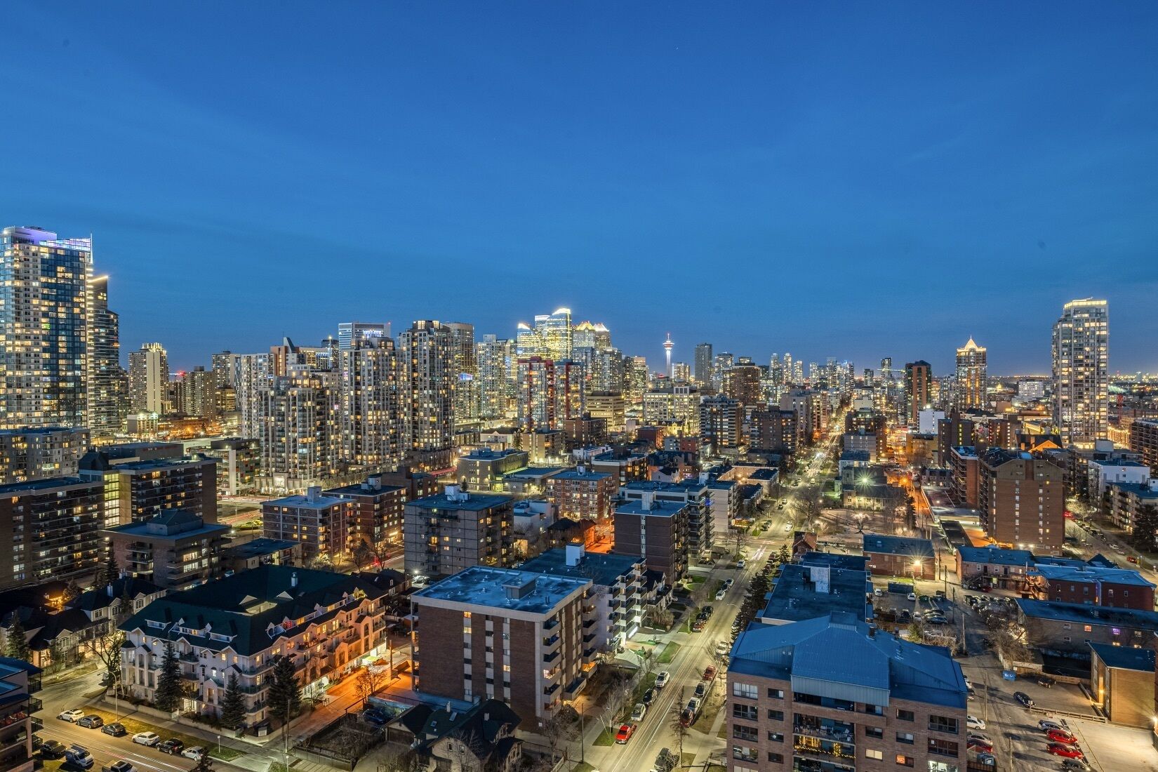 A cityscape at dusk with high-rise buildings, roads, and a mix of residential and commercial structures.