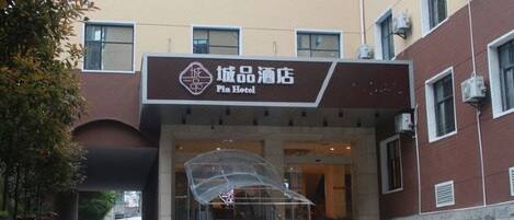 A hotel entrance with a clear sign, a covered staircase, and a parking area.