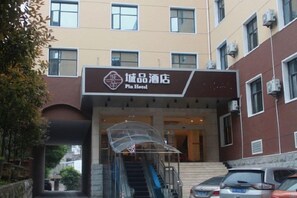 A hotel entrance with a clear sign, a covered staircase, and a parking area.