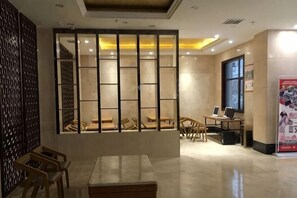 A hotel lobby with a reception desk, seating area, and a large window.