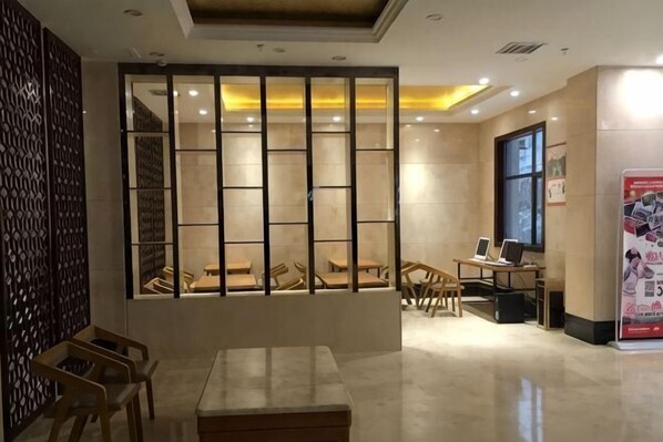 A hotel lobby with a reception desk, seating area, and a large window.