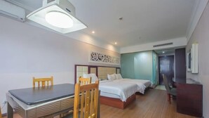 Ein Hotelzimmer mit einem Bett, einem Schreibtisch und einem Stuhl. An der Wand hängt ein Gemälde, und eine Tür führt in einen weiteren Raum.