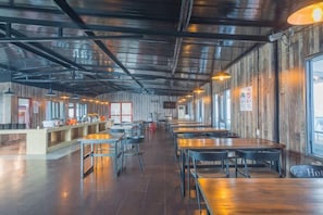 A spacious indoor dining area with long tables and chairs, a counter with a menu, and large windows along one wall. - Pin Hotel (Fuzhou)