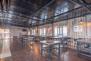 Un amplio comedor interior con numerosas mesas y sillas, paredes de madera y un techo alto.
