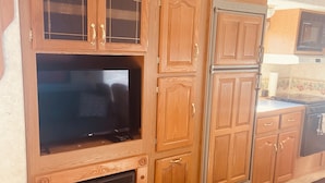 A kitchen with wooden cabinets, a built-in stove, and a television.