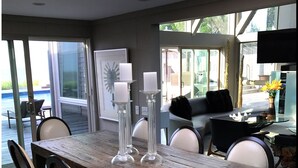 Un comedor con una mesa de madera, seis sillas y tres candelabros altos.