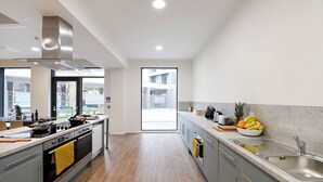 A modern kitchen with a central island, stainless steel appliances, and a large window providing natural light. - For Students Only Bright Ensuite at St Mungo's in Glasgow (Glasgow)