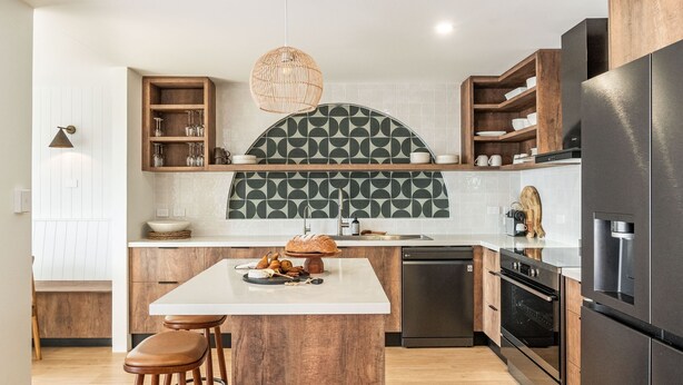 Une cuisine moderne dotée d’un îlot central, de meubles en bois et d’un réfrigérateur noir.