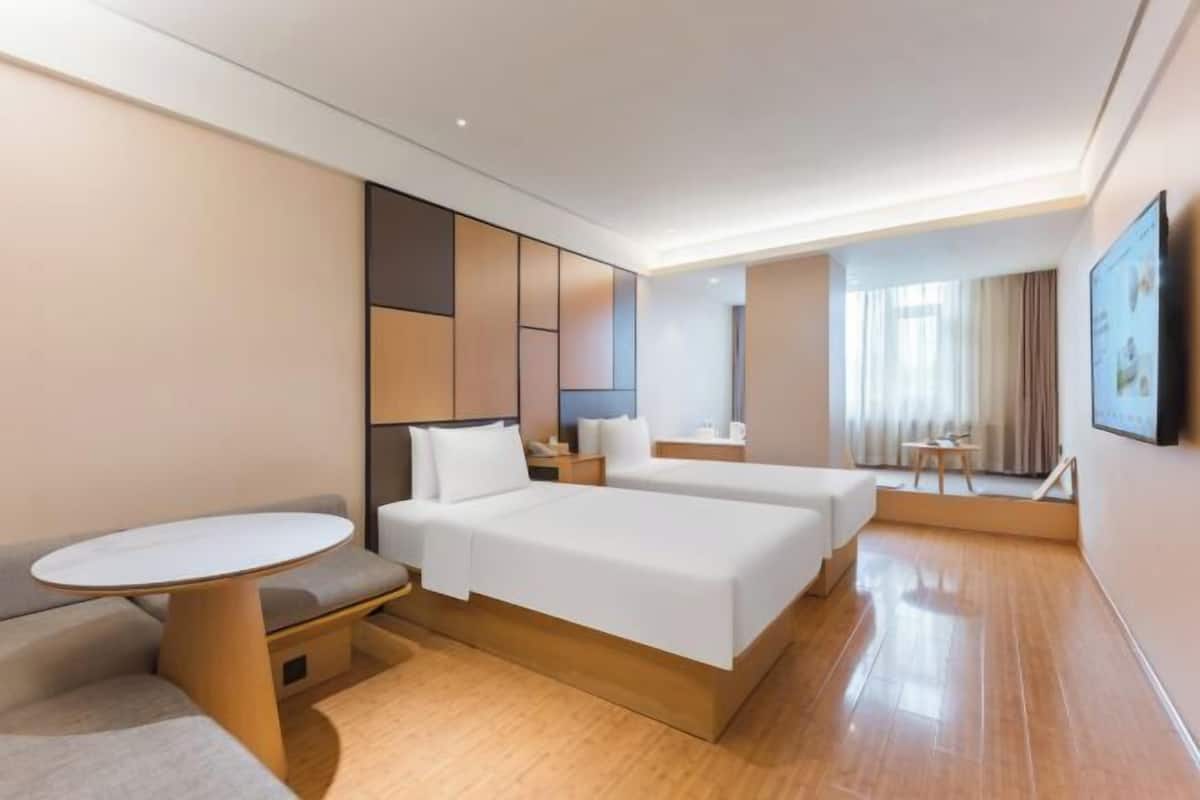 Ein Hotelzimmer mit Bett, Sofa, kleinem Tisch und Fernseher.