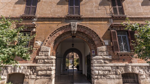 A historic building with a stone facade, arched entrance, and multiple windows with shutters. - DELUXE Suite, stunning view of the Tiber River. Top floor with elevator (Roma)