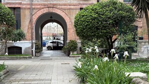 A paved pathway leading to a brick archway, surrounded by greenery and white flowers. - DELUXE Suite, stunning view of the Tiber River. Top floor with elevator (Roma)